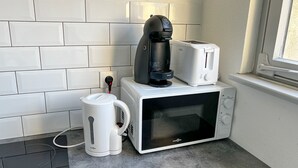 A kitchen with a white tiled backsplash, a white countertop, a coffee maker, a toaster, and a microwave. - New Studio - City Center Mulhouse - Near Train station (Mulhouse)