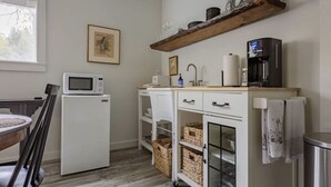 Eine kompakte Küche mit Mikrowelle, Kaffeemaschine und einer Anrichte mit Geschirr.