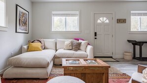 Ein Wohnzimmer mit einem weißen Sofa, einem Couchtisch und einer Tür mit Fenster.