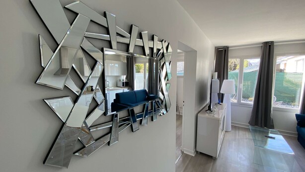 A modern living room with a geometric wall art installation, a blue sofa, and a glass coffee table. - #Casafouilloy Apartment with large terrace (Fouilloy)