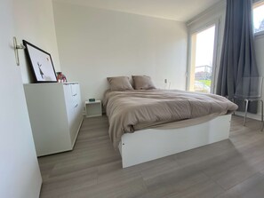 A modern bedroom with a bed, a small bedside table, a wardrobe, and a window with curtains. - #Casafouilloy Apartment with large terrace (Fouilloy)