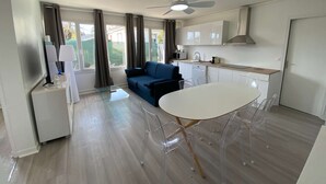 A modern kitchen with white cabinets, a dining table with clear chairs, a blue sofa, and a ceiling fan. - #Casafouilloy Apartment with large terrace (Fouilloy)