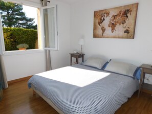 Un dormitorio con cama, mesita de noche, lámpara, ventana y un mapa del mundo en la pared.