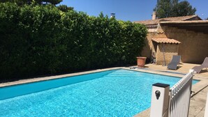 A rectangular swimming pool with clear blue water, surrounded by a low hedge and a tiled wall. - Detached house + private pool located 5 mn from Avignon and 15 mn from St Rémy (Les Angles)