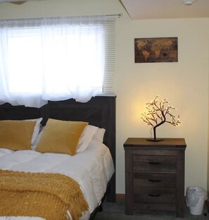 A bedroom with a bed, a nightstand, a lamp, and a painting on the wall. - Holistic Hideaway (Cheboygan)