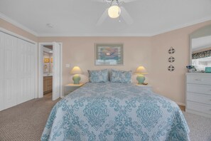 A bedroom with a bed, two bedside lamps, a ceiling fan, a framed picture on the wall, and a white dresser. - Shorehaven Lakefront & Steps to Beach w Pool (North Myrtle Beach)