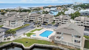 Zona residencial con piscina rodeada por una cerca blanca, un muelle y vistas al océano.