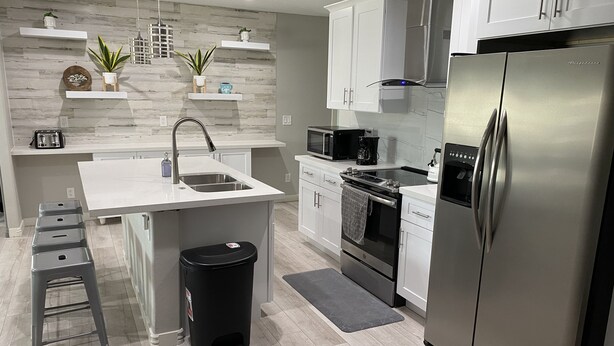 Una cocina moderna con armarios blancos, electrodomésticos de acero inoxidable y una isla central con fregadero.