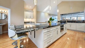 A modern kitchen with a large island, white cabinetry, and pendant lighting. - ★ HostWise Stays ★ Skyline Splendor w/ Private Balconies & Game Room (Pittsburgh)