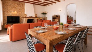 Un coin repas avec une table en bois dressée pour quatre personnes, entourée de chaises à motifs.