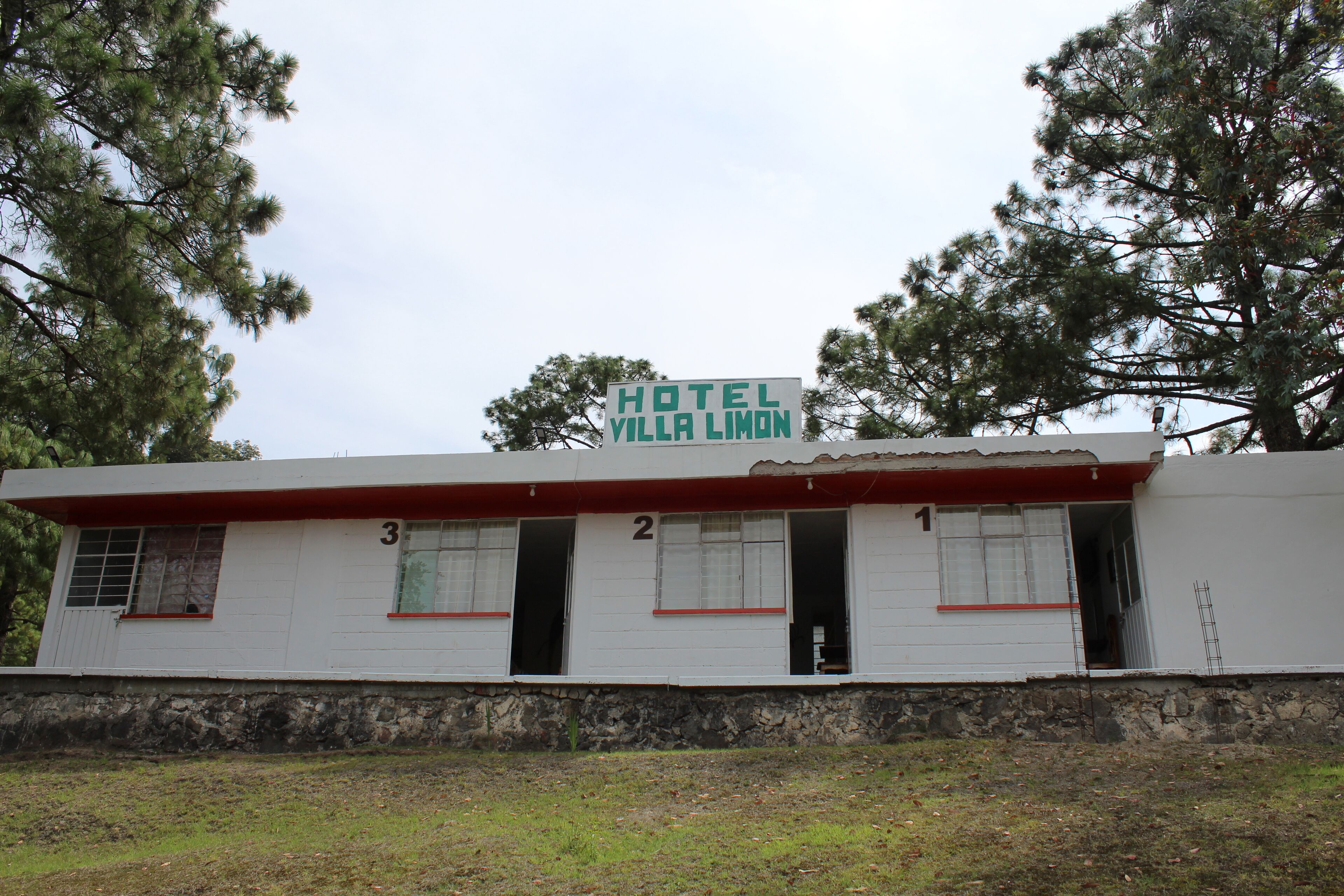 A white building with a red roof and a sign that reads "HOTEL VILLA LEMON".