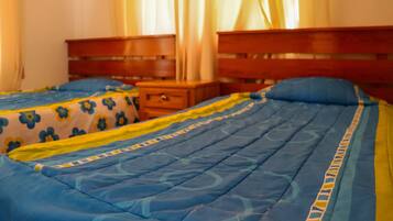 Un dormitorio con dos camas, cada una con una colcha de flores azules y amarillas.