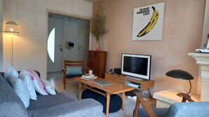Un soggiorno con un divano, un tavolino, una televisione e una lampada.
