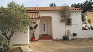 Una casa con tetto in tegole, facciata bianca e area d'ingresso pavimentata.