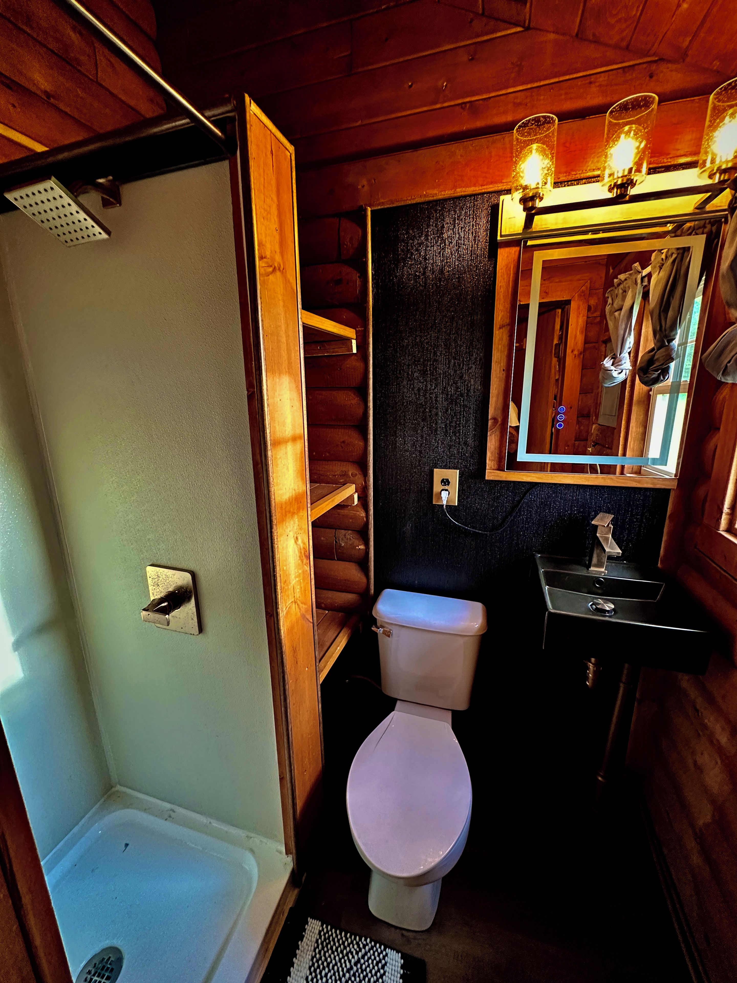 Een kleine badkamer met douche, toilet en wastafel.