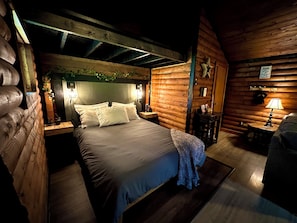 Une chambre confortable dans un chalet en rondins, avec un lit, des tables de chevet, une lampe et un mur en bois.
