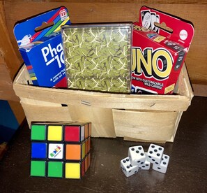 A wooden box containing a Rubik's Cube, a deck of UNO cards, and a pack of dominoes. - Bear Lodge: Pet-Friendly Tiny Cabin Near Cook Forest & Allegheny National Forest (Marienville)