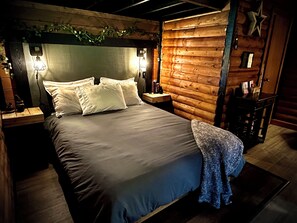 Una cama con cabecera, mesitas de noche y una mesita auxiliar con lámpara.