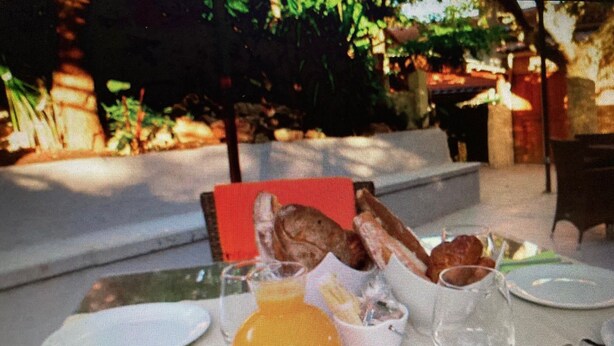 A table set for breakfast with plates, glasses, and a basket of bread. - Auberge Sainte Marguerite - "Anse Méjean" room (La Garde)
