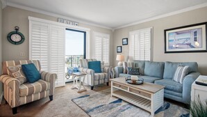 Un salon avec des fauteuils à rayures, un canapé bleu et une table basse.