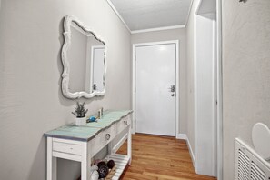 A bathroom with a wooden vanity, a large mirror, and a white door. - Luxury condo with a view (Myrtle Beach)