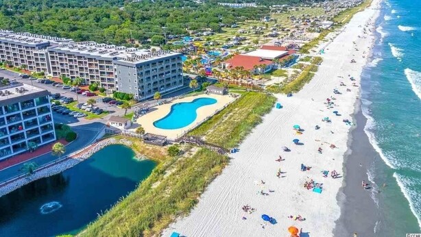 Un hôtel situé sur la côte, doté d’une piscine, d’une plage et offrant une vue sur l’océan.