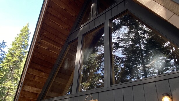 Une cabane avec un toit en pente, de grandes fenêtres et une pancarte indiquant : « Bienvenue à la Perche ».