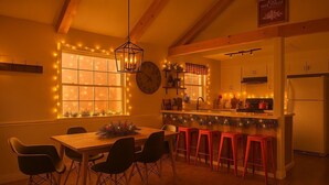 Una cocina acogedora con comedor, vigas de madera, un reloj y luces festivas.