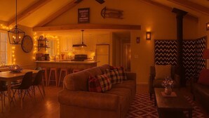 Una sala de estar acogedora con un sofá, un comedor con una mesa de madera y sillas, una cocina con armarios de madera y un ventilador de techo.