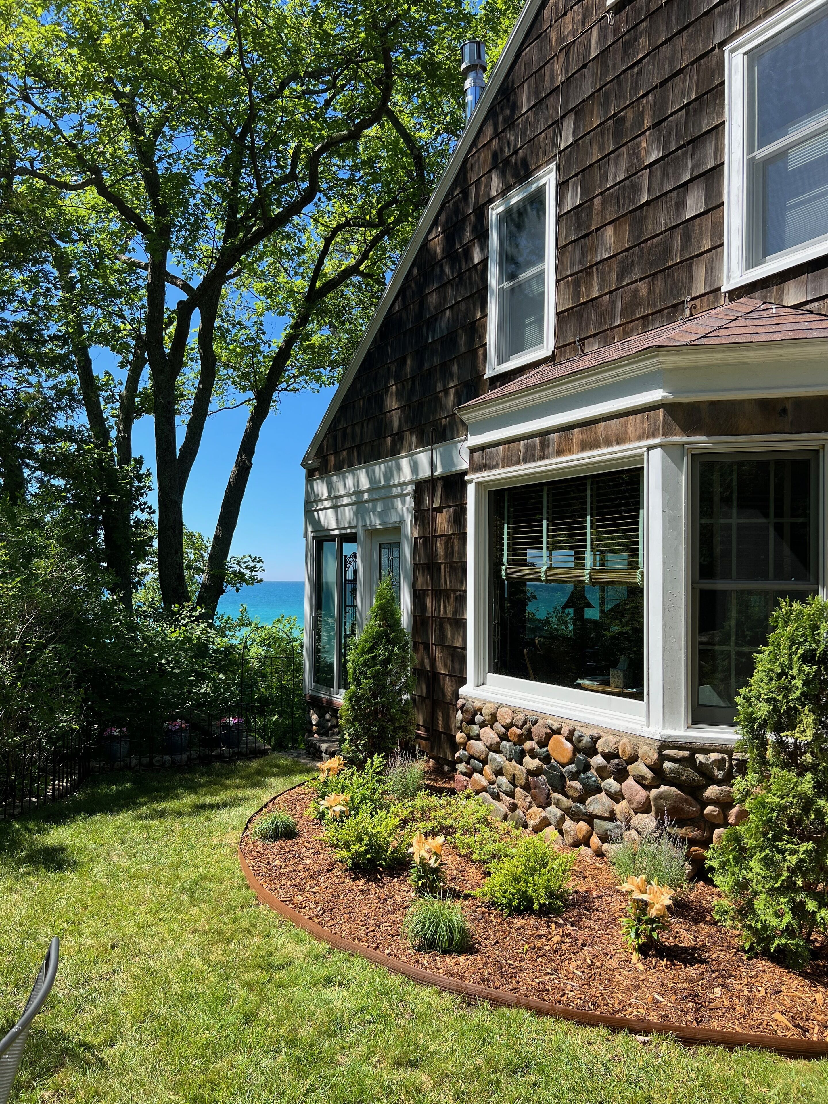 A two-story house with a stone foundation and a well-maintained garden.