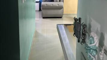 Une chambre d’hôtel avec un canapé, une salle de bain avec un miroir et un sol carrelé.