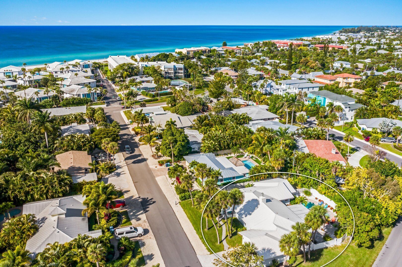 An aerial view of a coastal residential area with houses, roads, and a beach.