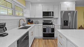 Une cuisine moderne avec des armoires blanches, des appareils en acier inoxydable et un plancher en bois.