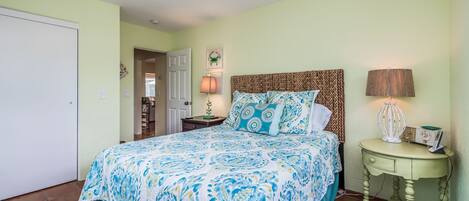 A bedroom with a bed, a nightstand, a lamp, and a ceiling fan.