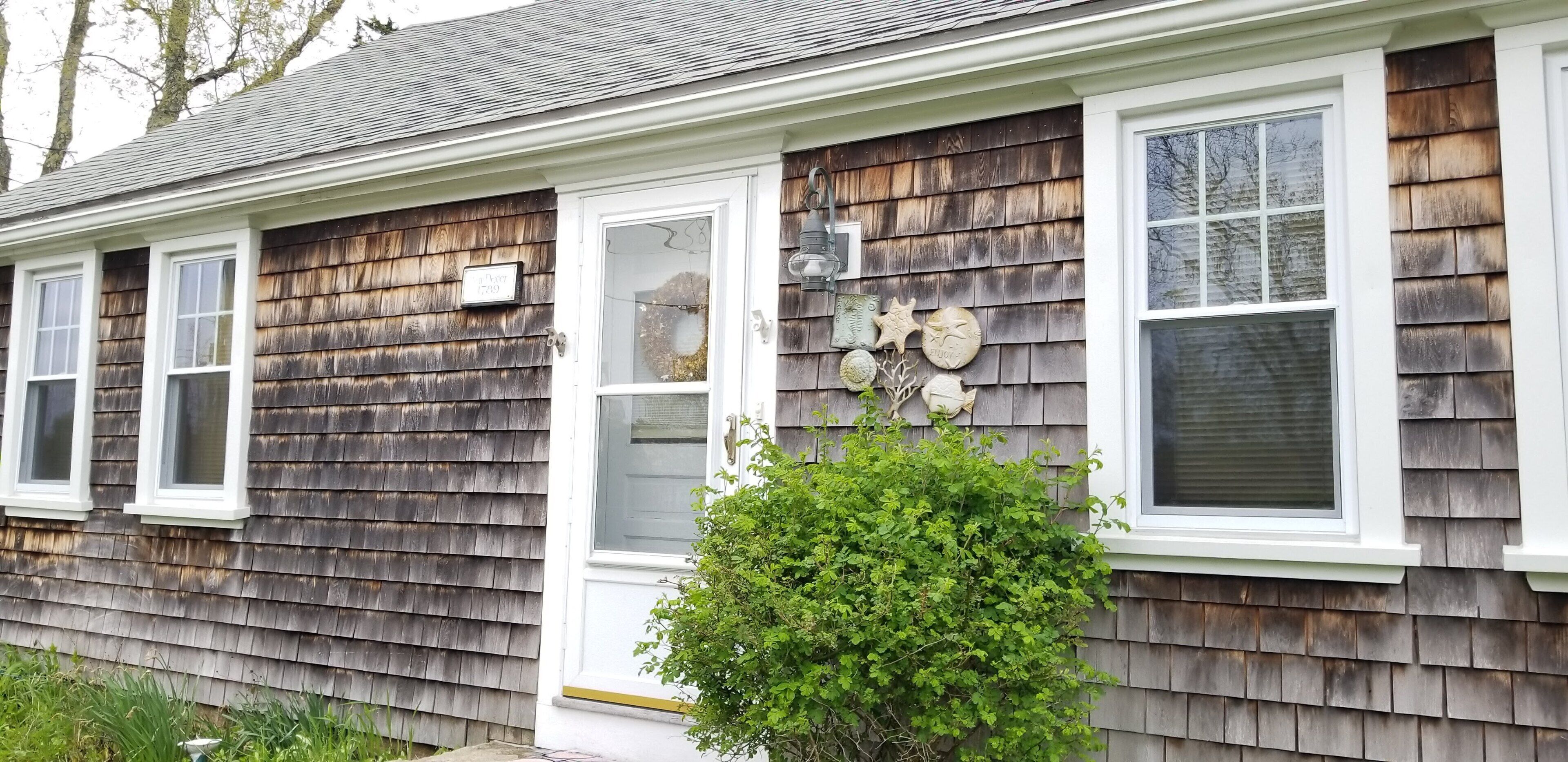 A house with a shingled exterior, white trim, and multiple windows.