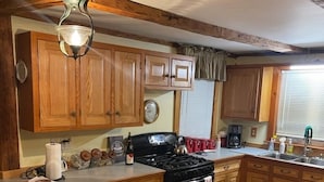 A kitchen with wooden cabinets, a large island, a stove, and a sink.