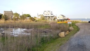 A coastal property with a large house, a gravel path, and a beach area with canoes.