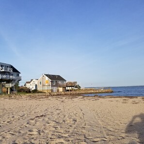 Une plage avec des maisons, un mur de pierre et un ciel dégagé.