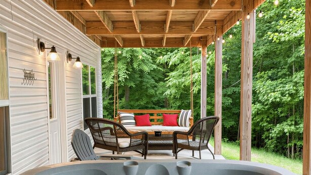 A hot tub with a wooden deck and outdoor furniture, surrounded by greenery. - 4 Bedroom Lakehouse w/ Hot Tub, Firepit, & Game Room (Cadiz)