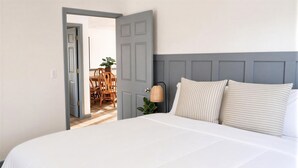 A bedroom with a bed, a nightstand, a lamp, and a view into a dining area. - 4 Bedroom Lakehouse w/ Hot Tub, Firepit, & Game Room (Cadiz)