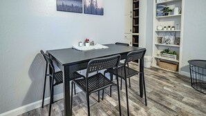 Un coin repas avec une table et des chaises, une bibliothèque et une porte donnant sur une autre pièce.