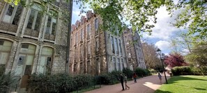 A historic building with stone facade and arched windows, surrounded by a pathway and greenery.