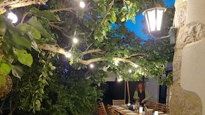 Un área de comedor al aire libre con pared de piedra, piso de baldosas e iluminación colgante.
