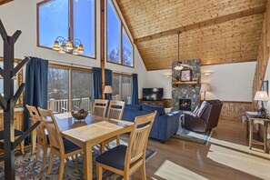 Cozy living area with a large dining table, comfortable seating, and a stone fireplace.
