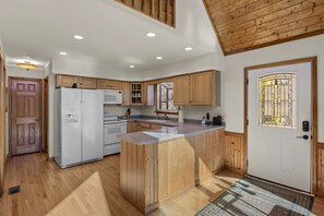 Kitchen features a central island, appliances, and a large window with an outdoor view.