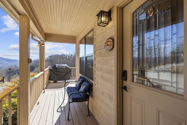 Relax on the covered porch with a scenic mountain view, perfect for outdoor dining or relaxation.
