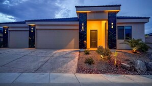 A modern house with a well-lit entrance, a driveway, and a landscaped front yard. - Chill. Grill. Putt. Splash. Play. Your Private Pool Paradise Awaits! (Mesquite)