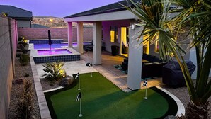 A modern outdoor patio with a pool, artificial grass, and seating areas. - Chill. Grill. Putt. Splash. Play. Your Private Pool Paradise Awaits! (Mesquite)