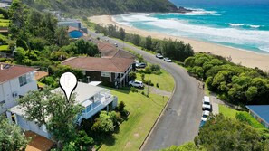 A coastal residential area with houses, a road, and a beach.