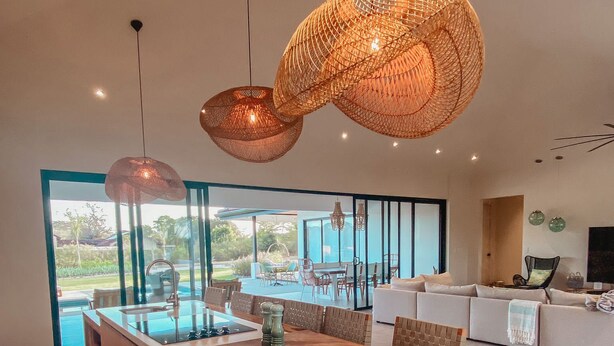 A spacious kitchen with a wooden island, large windows, and hanging woven light fixtures. - Casa Palmeras • Luxury Villa Near Beach & Surf (Tamarindo)